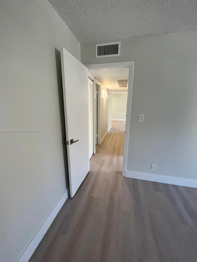 corridor with hardwood / wood-style floors and a textured ceiling