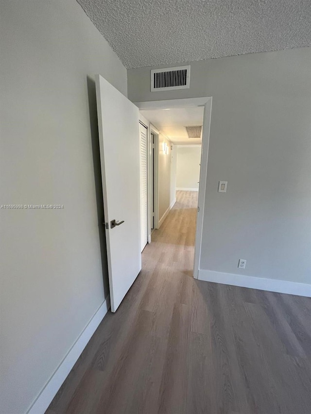 401 Golden Isles Dr Unit 303, Hallandale Beach, FL 33009 - hallway featuring wood finished floors, baseboards, and a textured ceiling