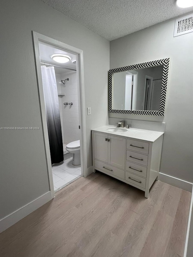 bathroom featuring curtained shower, a textured ceiling, toilet, vanity, and hardwood / wood-style flooring