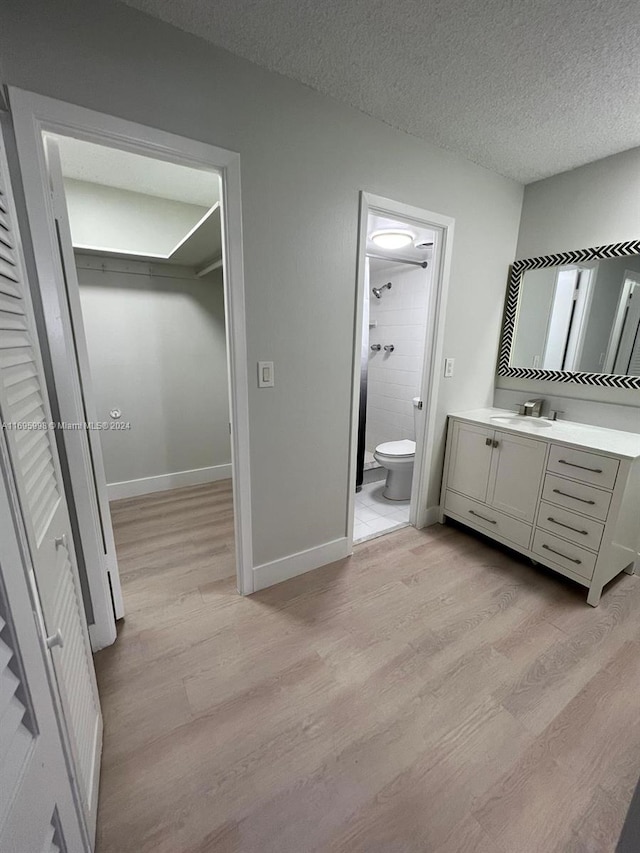 bathroom featuring vanity, hardwood / wood-style floors, a textured ceiling, and a tile shower