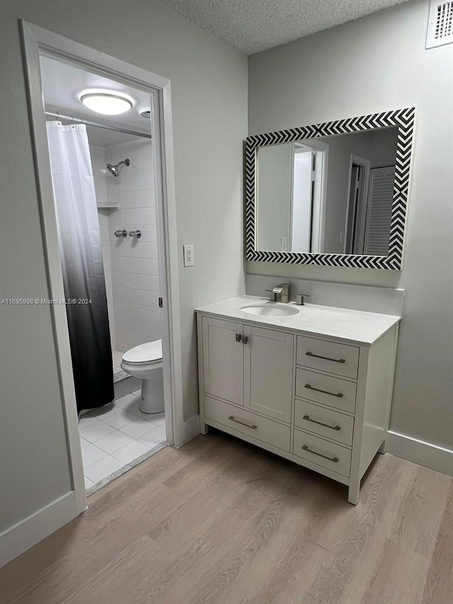 bathroom featuring curtained shower, vanity, wood-type flooring, and a textured ceiling