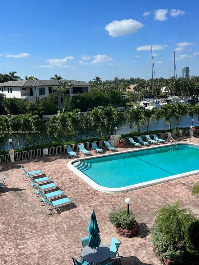 view of swimming pool featuring a water view and a patio area