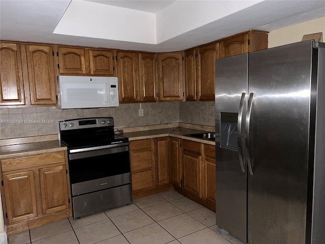 kitchen featuring appliances with stainless steel finishes, light tile patterned floors, and tasteful backsplash