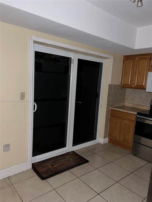 kitchen with stainless steel range with electric cooktop, light tile patterned floors, and tasteful backsplash