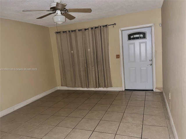 tiled foyer entrance with a textured ceiling and ceiling fan