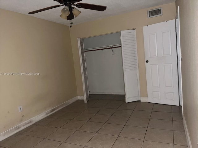 unfurnished bedroom featuring ceiling fan, tile patterned flooring, and a closet