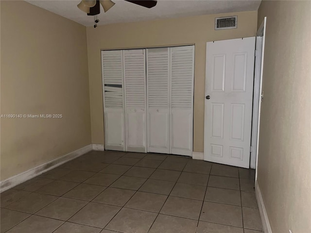 unfurnished bedroom with ceiling fan, tile patterned flooring, and a closet