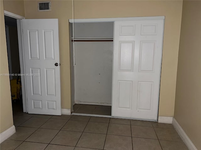 unfurnished bedroom featuring dark tile patterned floors and a closet