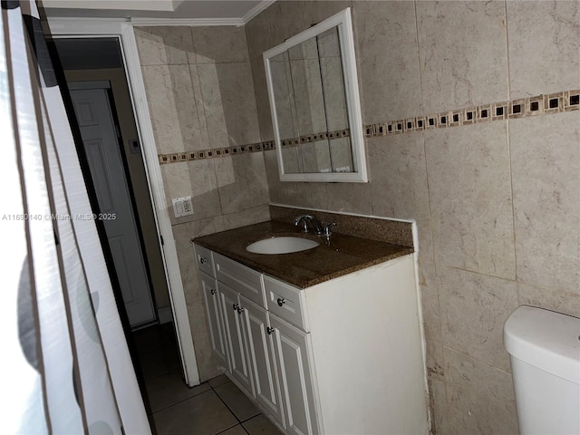 bathroom featuring tile patterned flooring, toilet, vanity, tile walls, and ornamental molding