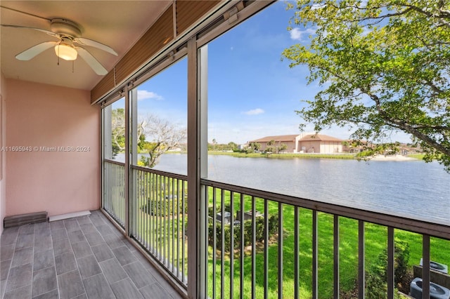 unfurnished sunroom featuring ceiling fan and a water view