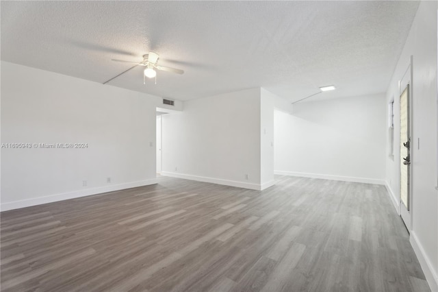 empty room with ceiling fan, dark hardwood / wood-style flooring, and a textured ceiling