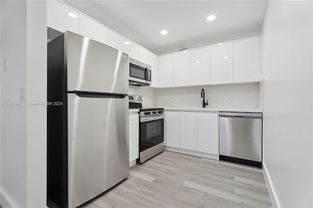 kitchen with white cabinets, appliances with stainless steel finishes, light wood-type flooring, and sink