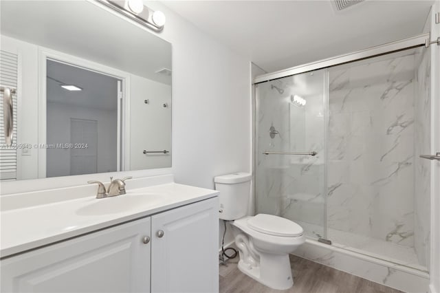 bathroom featuring walk in shower, toilet, vanity, and hardwood / wood-style flooring