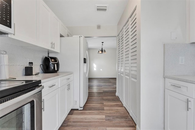 kitchen featuring stainless steel electric stove, wood-type flooring, white cabinetry, and tasteful backsplash