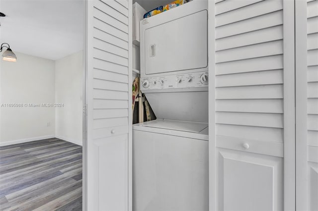 laundry room with hardwood / wood-style floors and stacked washer / drying machine