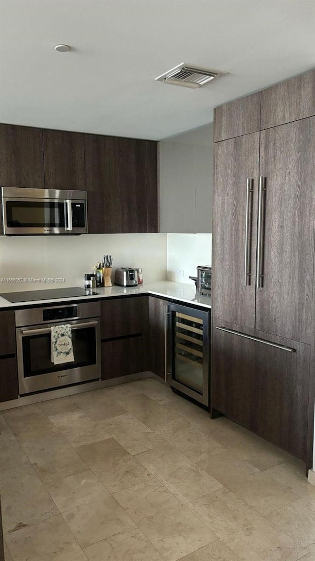 kitchen with appliances with stainless steel finishes, dark brown cabinetry, and wine cooler