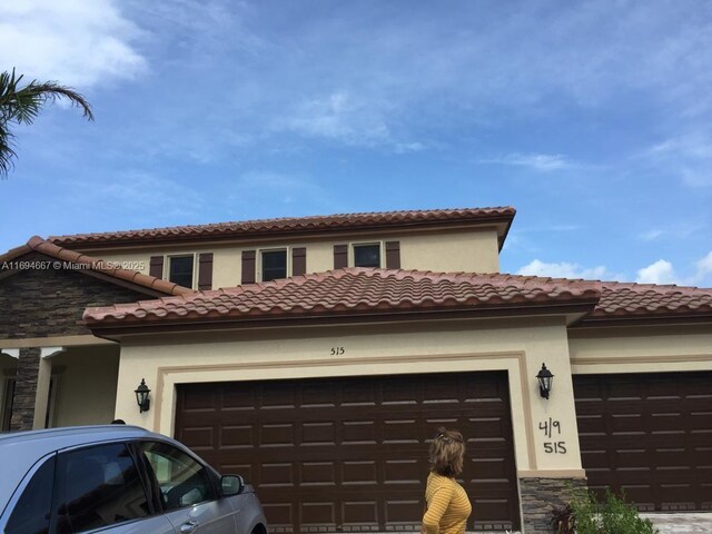 515 SE 35th Ave, Homestead, FL 33033 - view of front of house featuring a garage, a tiled roof, stone siding, and stucco siding