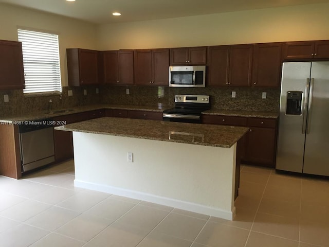 kitchen with a center island, dark stone counters, decorative backsplash, appliances with stainless steel finishes, and light tile patterned flooring