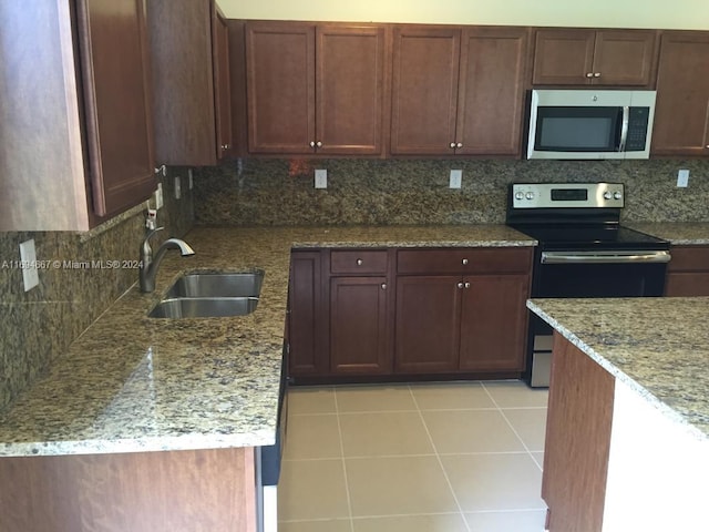 kitchen with sink, decorative backsplash, light stone countertops, light tile patterned floors, and stainless steel appliances