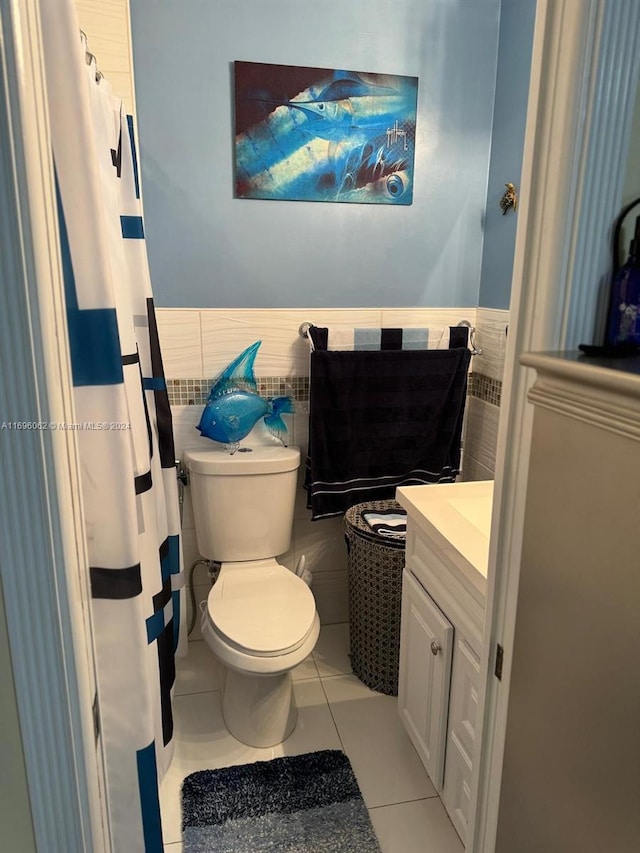 bathroom with tile patterned flooring, vanity, toilet, and tile walls