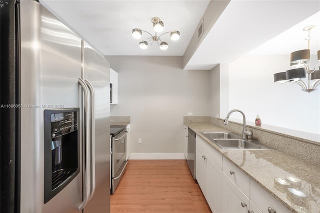 kitchen with sink, light stone countertops, appliances with stainless steel finishes, light hardwood / wood-style floors, and white cabinetry