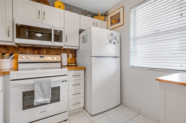 kitchen with white appliances, white cabinetry, a healthy amount of sunlight, and light tile patterned flooring