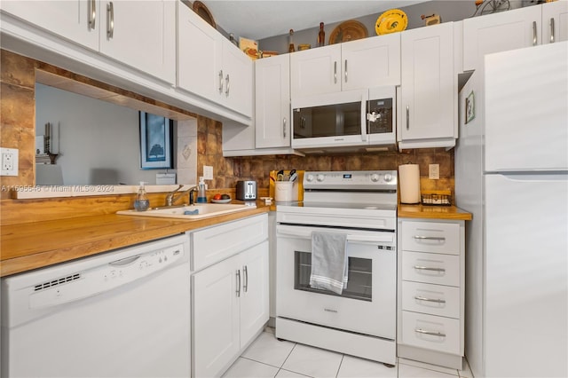 kitchen with white cabinetry, sink, light tile patterned floors, and white appliances