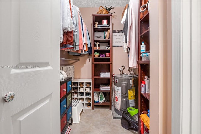 spacious closet with light tile patterned floors and electric water heater