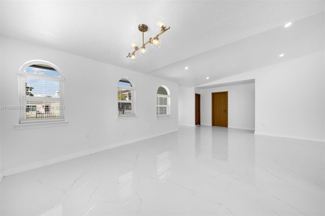 empty room with a textured ceiling, an inviting chandelier, and plenty of natural light