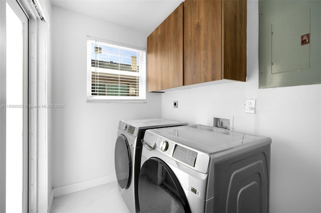 laundry room with cabinets, washing machine and dryer, and electric panel