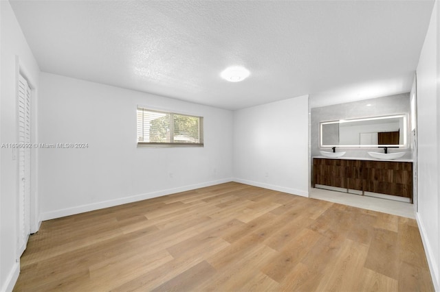 unfurnished bedroom with a textured ceiling and light hardwood / wood-style flooring