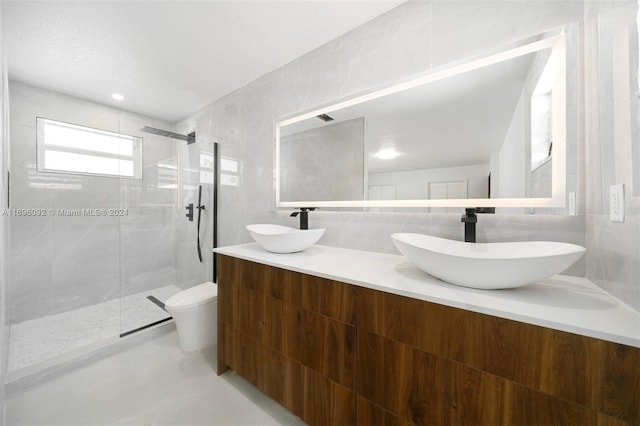 bathroom with vanity, tile patterned floors, toilet, tiled shower, and tile walls