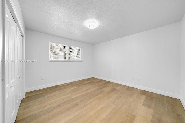 unfurnished bedroom with a closet, light hardwood / wood-style floors, and a textured ceiling