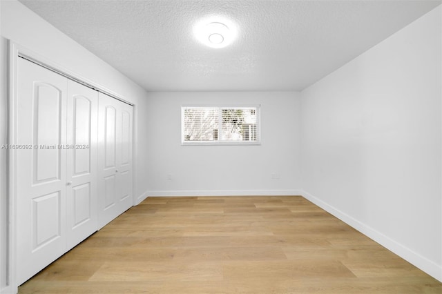 unfurnished bedroom with a closet, light hardwood / wood-style floors, and a textured ceiling