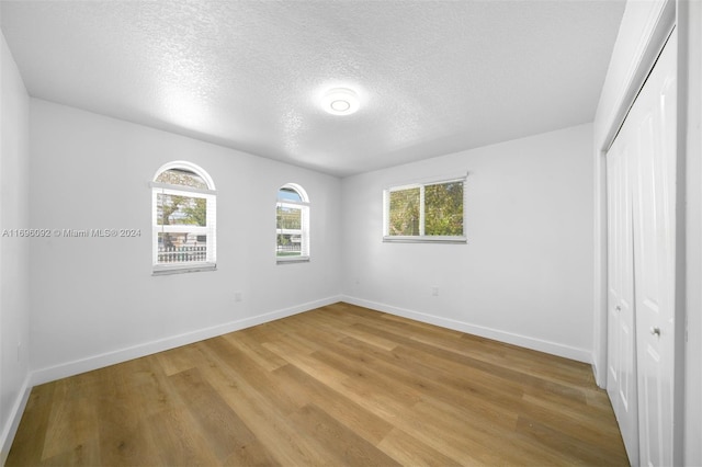 unfurnished bedroom featuring hardwood / wood-style flooring, a textured ceiling, and a closet