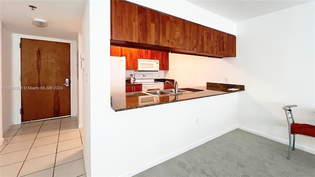 kitchen featuring kitchen peninsula, sink, light colored carpet, and white appliances