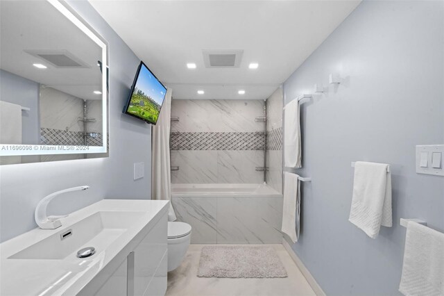 full bathroom featuring tiled shower / bath combo, toilet, and vanity