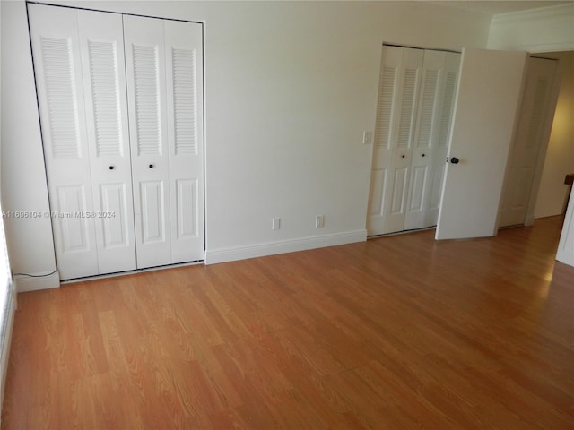 unfurnished bedroom with two closets and light hardwood / wood-style flooring