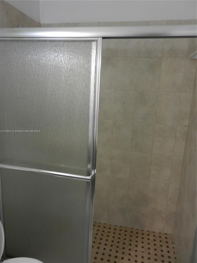 bathroom featuring a shower with shower door and toilet