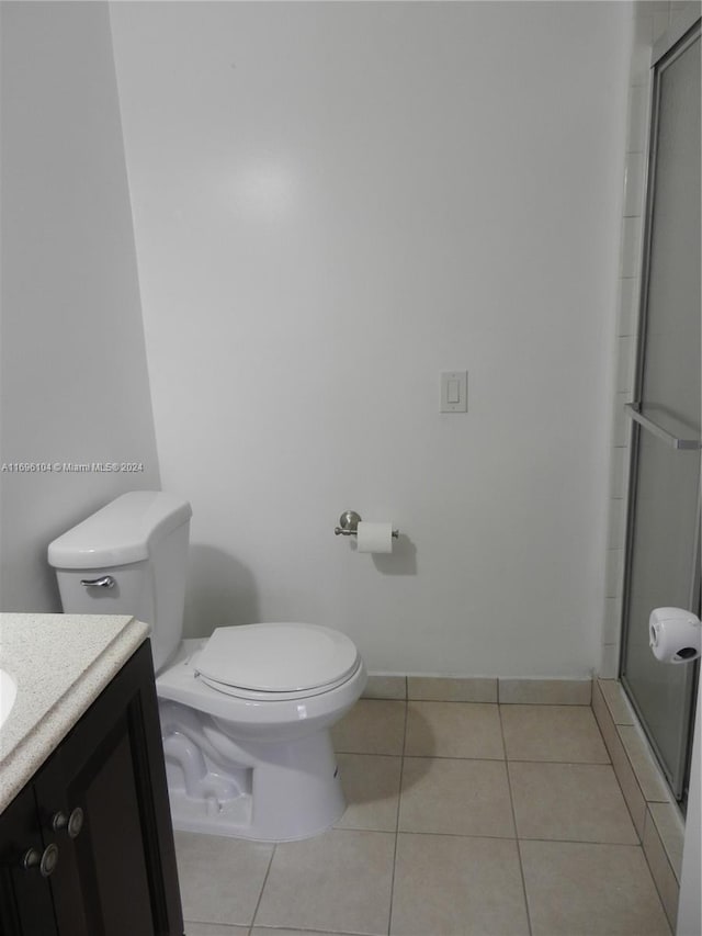 bathroom featuring tile patterned floors, vanity, toilet, and a shower with door