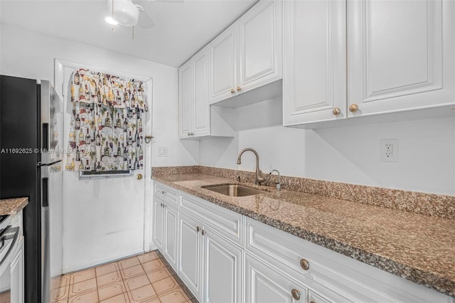 17000 NE 14th Ave Unit 301, North Miami Beach, FL 33162 - kitchen featuring freestanding refrigerator, a sink, white cabinets, dark stone countertops, and a ceiling fan