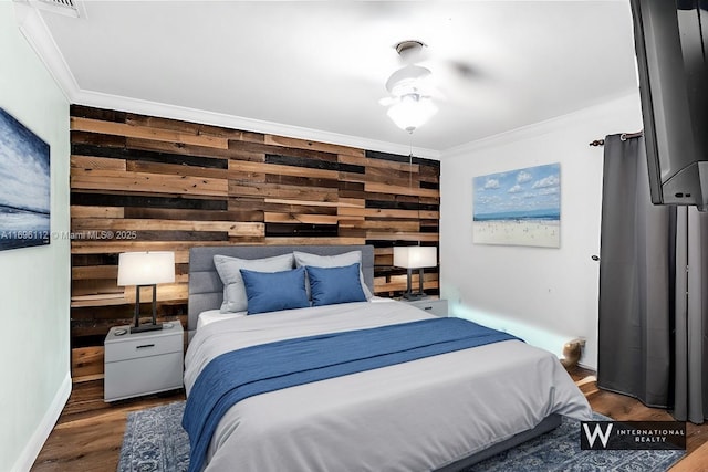 bedroom featuring hardwood / wood-style flooring, wooden walls, and ornamental molding