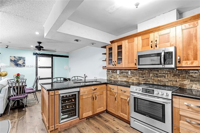 kitchen featuring wine cooler, appliances with stainless steel finishes, kitchen peninsula, and sink