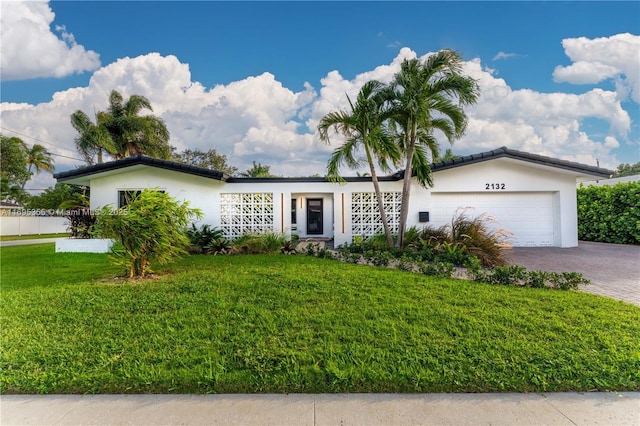 ranch-style house with stucco siding, an attached garage, decorative driveway, and a front yard