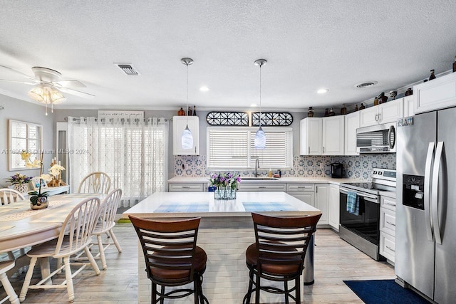 kitchen featuring a center island, white cabinetry, stainless steel appliances, and light hardwood / wood-style flooring