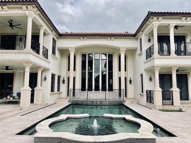 view of swimming pool featuring pool water feature, ceiling fan, and an in ground hot tub