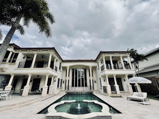 back of house with ceiling fan and a balcony