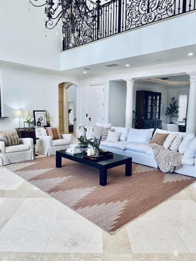 living room with a high ceiling, ornate columns, and ornamental molding