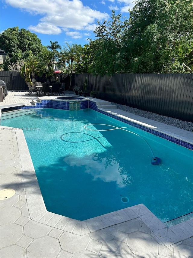 view of swimming pool with an in ground hot tub