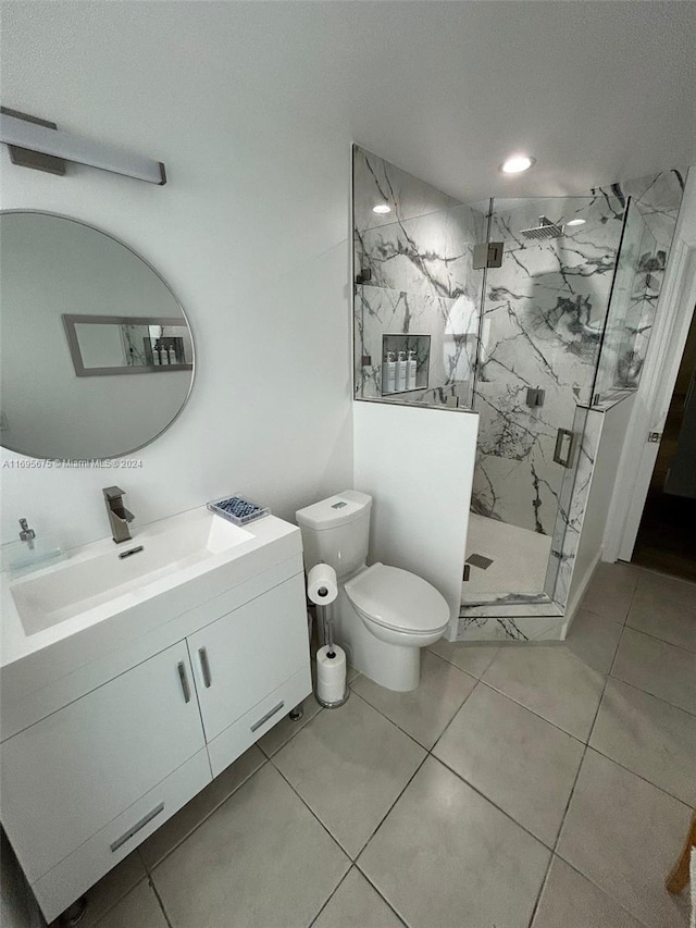 bathroom featuring tile patterned floors, vanity, toilet, and a shower with door